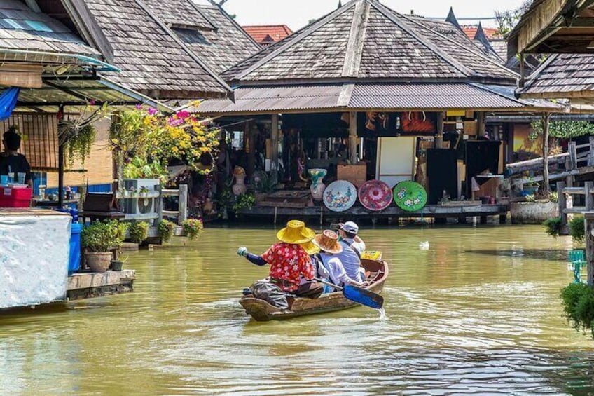Ein traditionelles Boot mit Passagieren auf einem Fluss, umgeben von Holzhäusern mit Strohdächern. 4