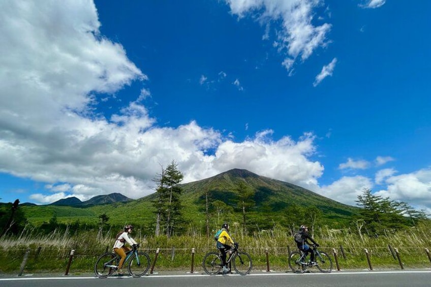 Three cyclists on a road with a mountain in the background. 2
