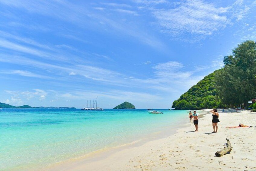 A beach with clear turquoise water, a sandy shore, and a small island in the distance. 4
