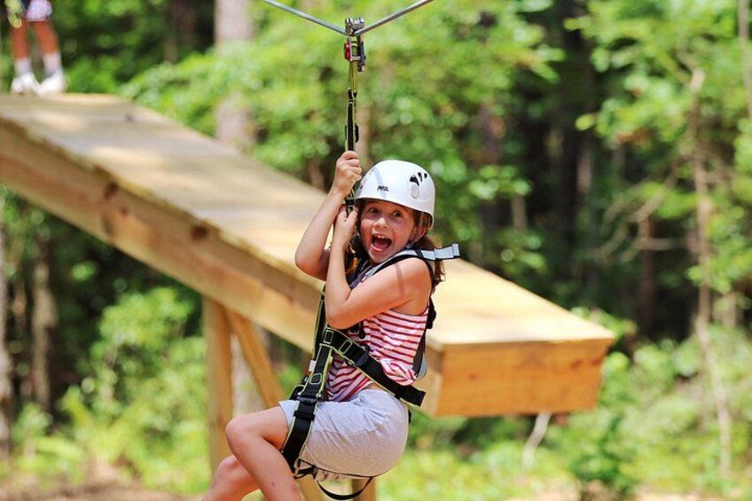 A person zip-lining through a forested area with wooden platforms. 5