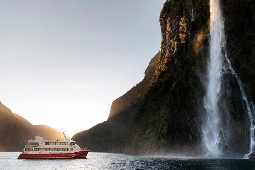 A boat on calm water with a waterfall in the background. 4