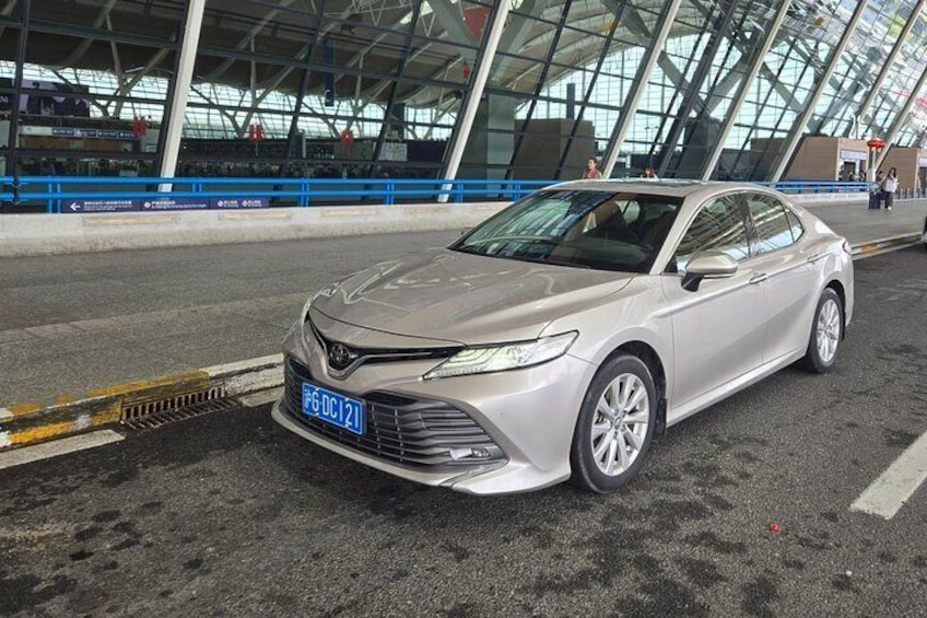 A silver sedan parked in a covered area with a blue license plate. 4