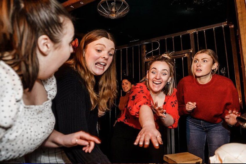 A group of people in a room with a wooden door and a metal gate. 2