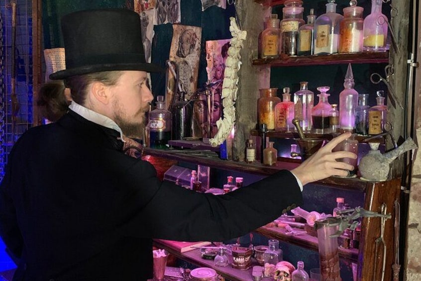 A person reaching for a shelf in a room filled with various bottles and glassware. 4