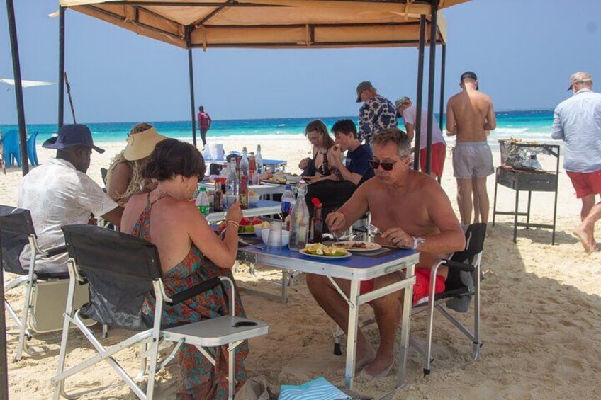 People dining at a beachside table with a view of the ocean. 3