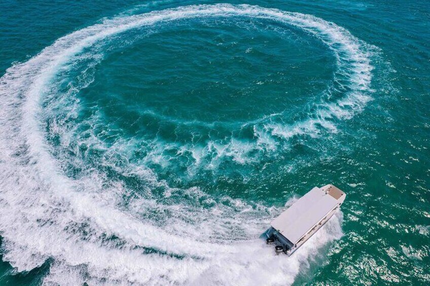 Un barco generando una estela circular en aguas oceánicas turquesas. 4
