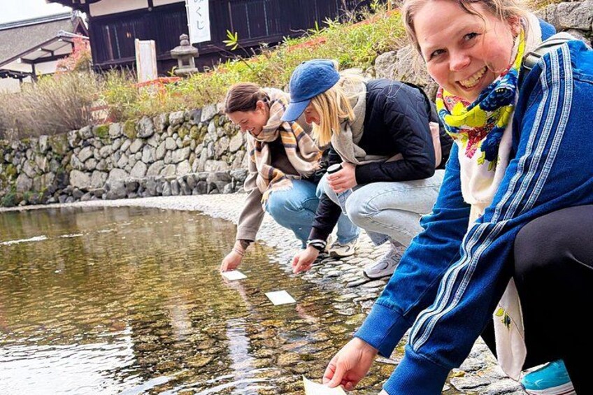 Three people by a pond, one person is bending over the water. 2