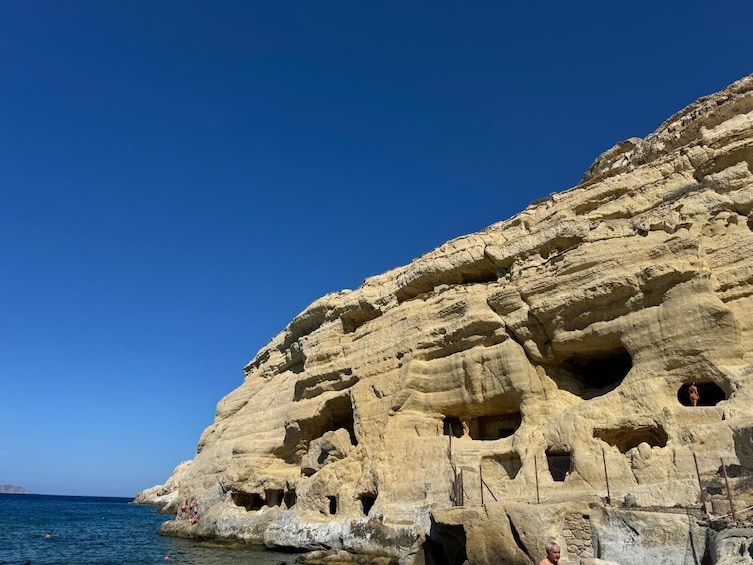 Een klif aan de kust met meerdere grotten en een helderblauwe lucht. 2
