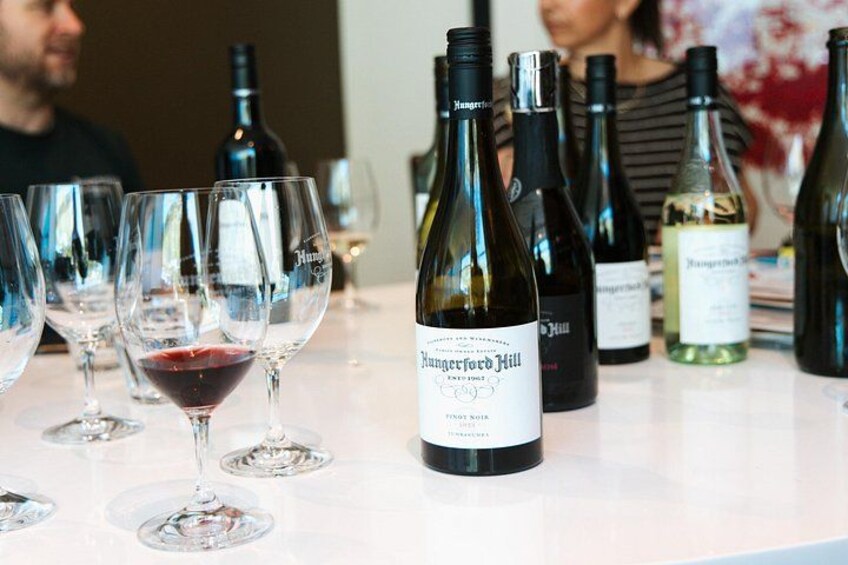 A wine tasting event with several wine bottles and glasses on a table. 4