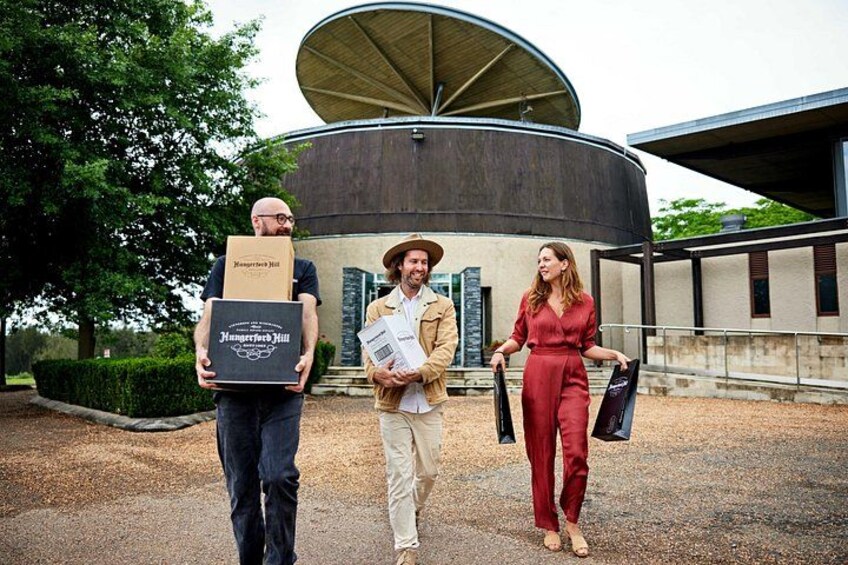 Three people carrying boxes, a building with a circular roof, and a landscaped area. 2