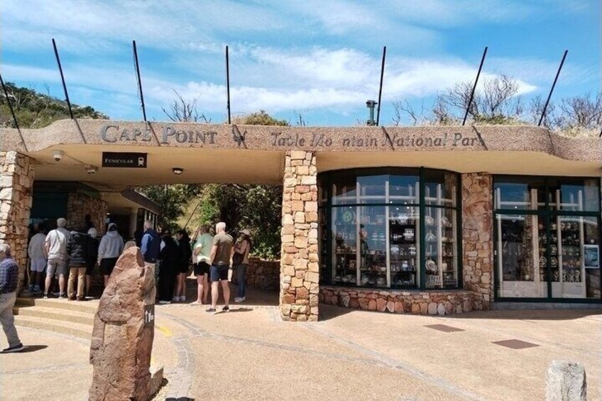 Ein steinerer Bogen mit dem Text 'Cape Point Table to the National Park' und einem Schild für 'Fencibles'. 1