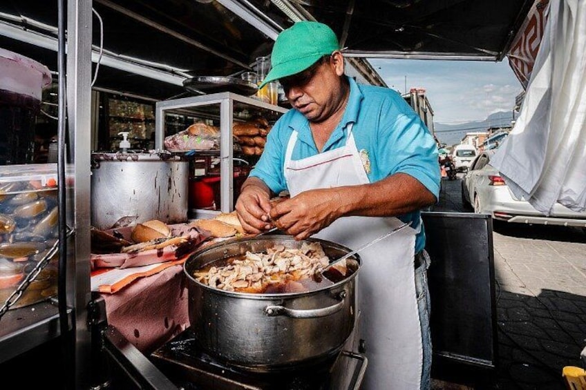 Una persona cocinando en un puesto de comida, con una olla y una parrilla. 5