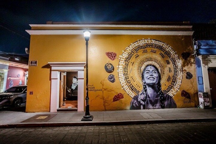 Un mural en un edificio de noche, con una mujer y un diseño circular de fondo. 4