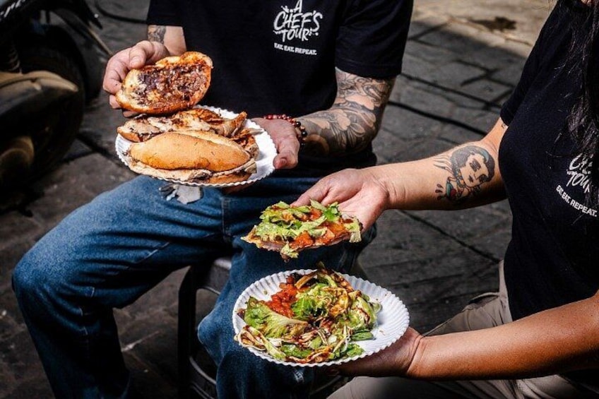 Personas sosteniendo alimentos, como sándwiches y una ensalada. 3