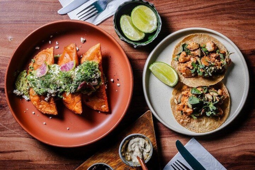 Una mesa de madera con dos platos de comida, uno con tacos y otro con plátanos fritos. 3