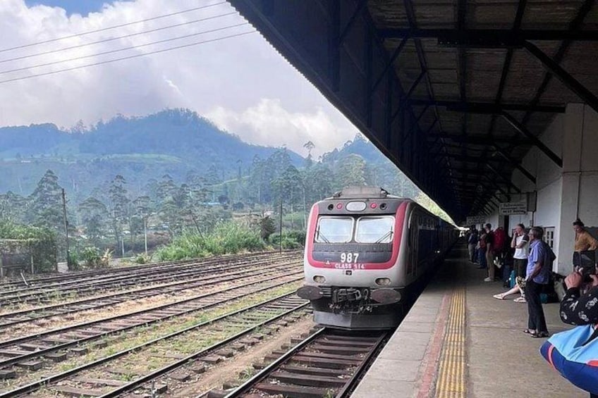 A train at a station with tracks, platform, and people waiting. 3
