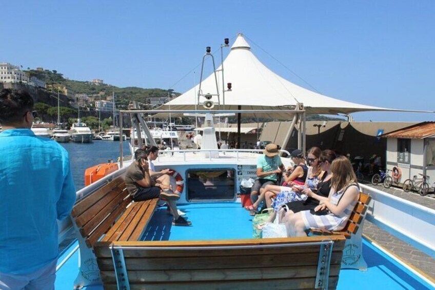 Un groupe de personnes se trouve sur un bateau doté d’un auvent blanc, qui est amarré dans une marina, avec des bâtiments en arrière-plan. 5