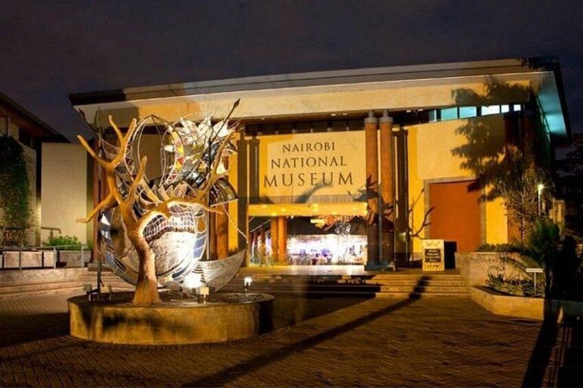 Das Nairobi National Museum bei Nacht mit einer großen Skulptur im Vordergrund. 2