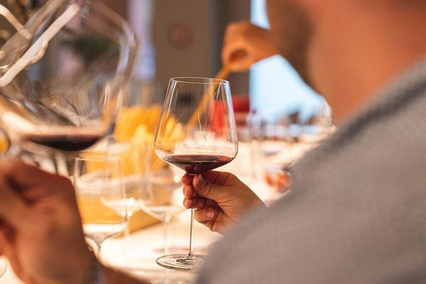 A person pouring red wine into a glass. 3