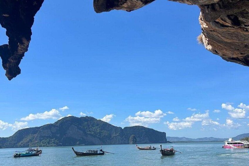 A coastal scene with boats on calm water, a large mountain in the background, and a clear blue sky. 2