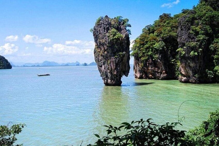 A clear blue sea with rock formations and a boat in the distance. 5