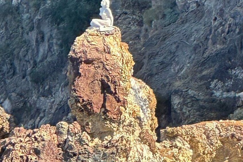 A rock formation with a statue of a seated figure on top. 5