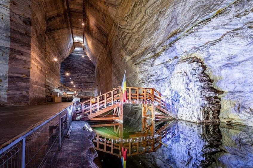 Eine Höhle mit einer Holztreppe und einer spiegelnden Wasseroberfläche. 3