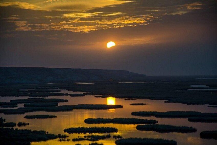 Un tramonto su una zona umida, con l'acqua che riflette il sole. 4