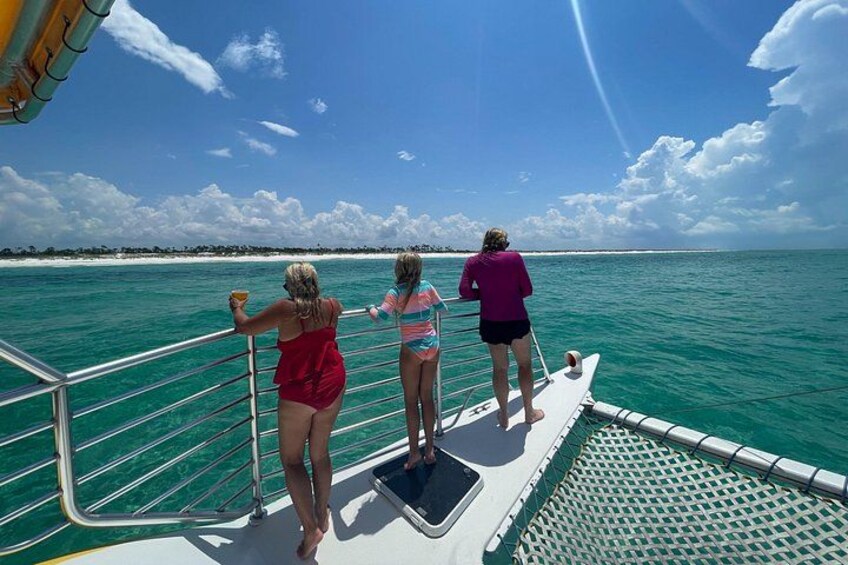 Tres personas en la cubierta de un barco, mirando aguas turquesas. 3