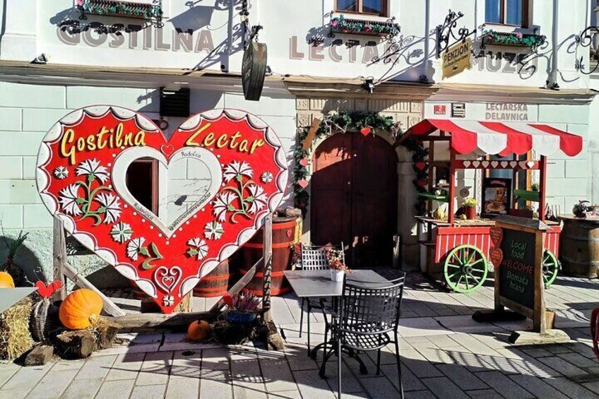 A heart-shaped sign with 'Gostilna' and 'Zectar' written on it, a street food cart, and a building with 'Gostilna' written on it. 5