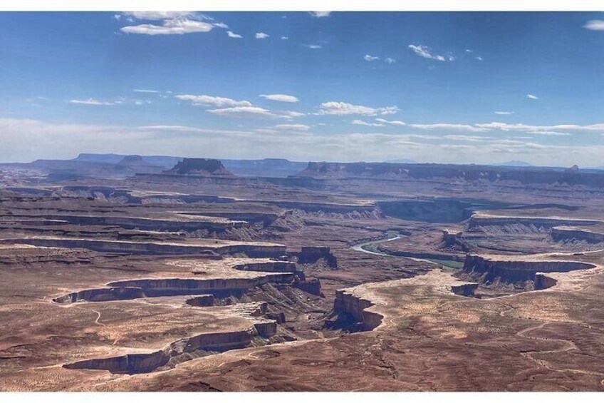 A vast canyon landscape with layered rock formations and a winding river. 3