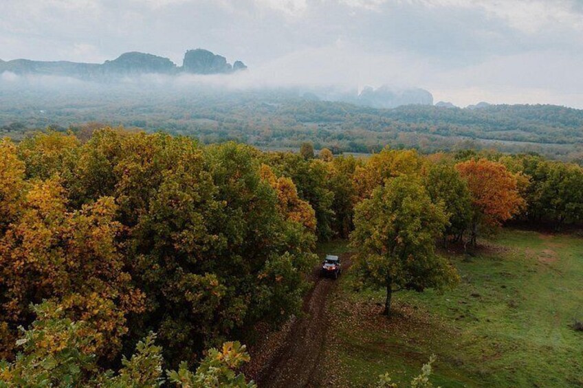 A vehicle on a rural road surrounded by autumn-colored trees. 1