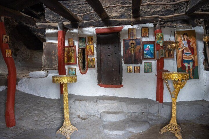 Un intérieur orné d’icônes religieuses, de décorations rouges et dorées, et de murs en pierre. 3