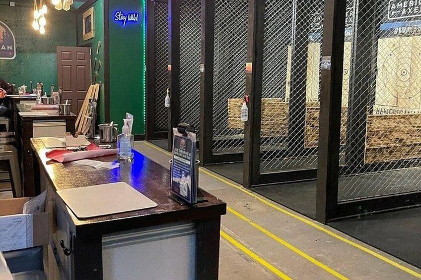 A bar counter with a neon sign, a green wall, and a chain-link fence in the background. 2
