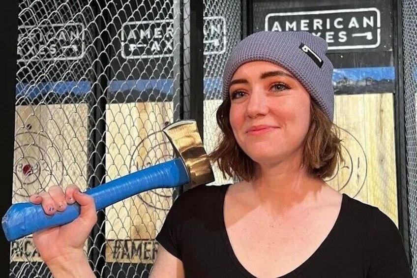 A person holding a blue bat in front of a chain-link fence with 'AMERICAN EXPRESS' signs. 2