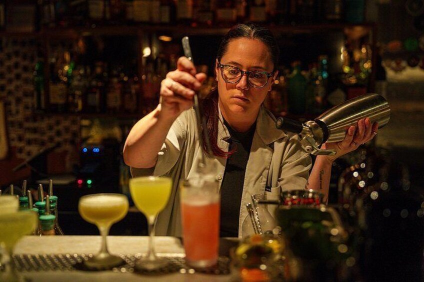 A bartender pouring a drink with a shaker in hand. 1