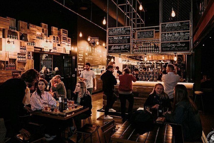 A bar with wooden crates, hanging lights, and people socializing. 5