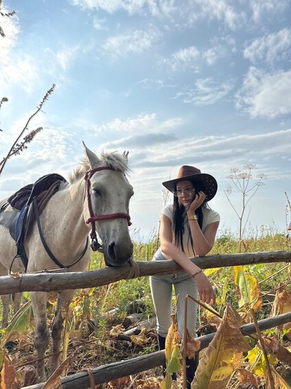 A person leaning on a fence with a white horse beside them. 2
