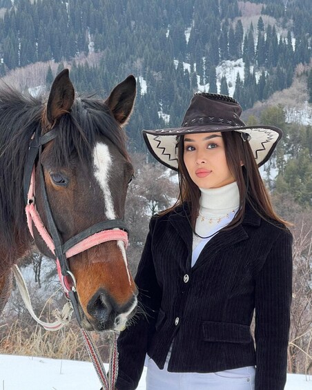 A person standing next to a horse with a snowy mountainous background. 3