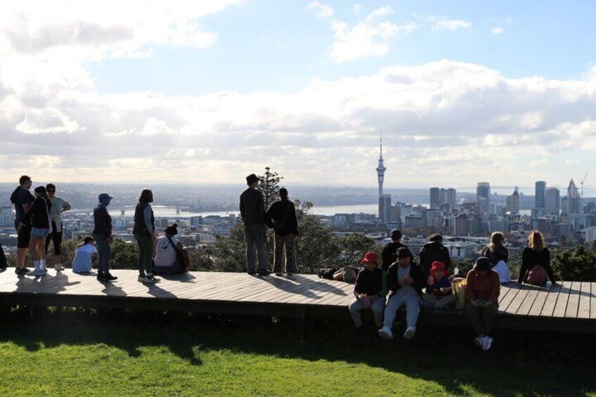 A group of people on a wooden platform overlooking a cityscape with a prominent tower. 4