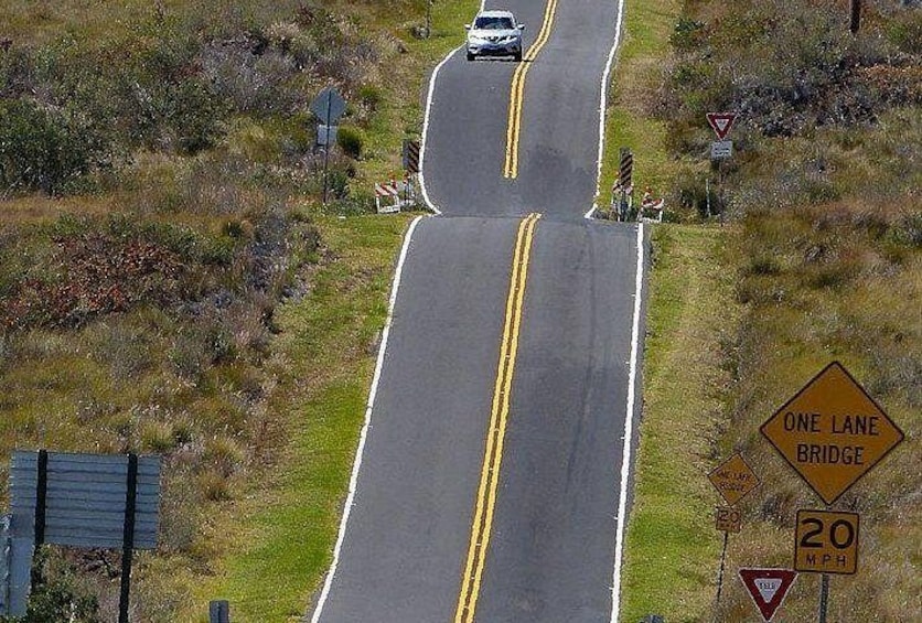 A two-lane road with a one-lane bridge warning sign, a speed limit sign, and a yield sign. 5