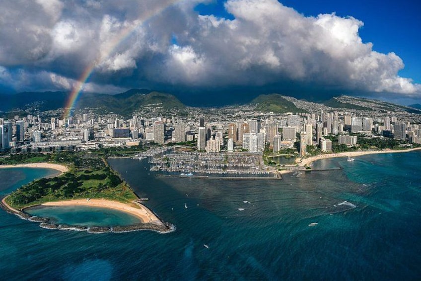 A coastal cityscape with a prominent beach, a marina, and a mountain range in the background. 3