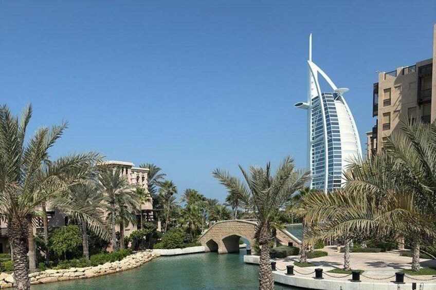 A coastal resort with palm trees, a bridge, and the Burj Al Arab hotel. 5