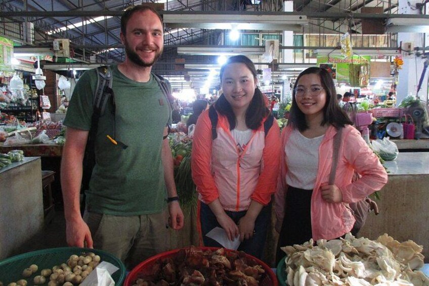 A market with people standing in front of stalls selling vegetables and other goods. 4