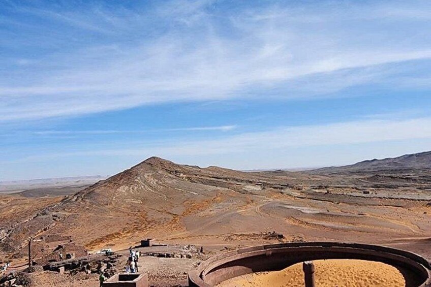 A barren landscape with a large hill, a circular structure, and a clear sky. 5