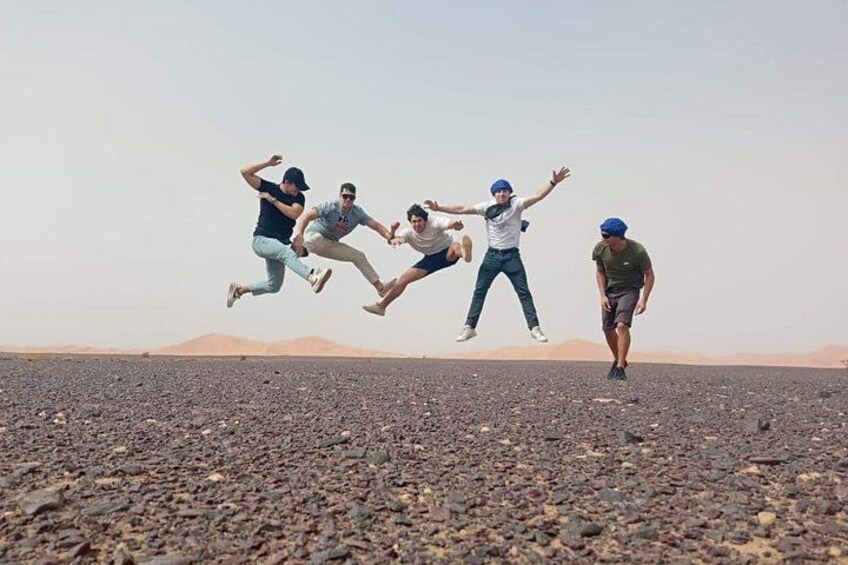 Four people jumping in a rocky landscape with mountains in the background. 2