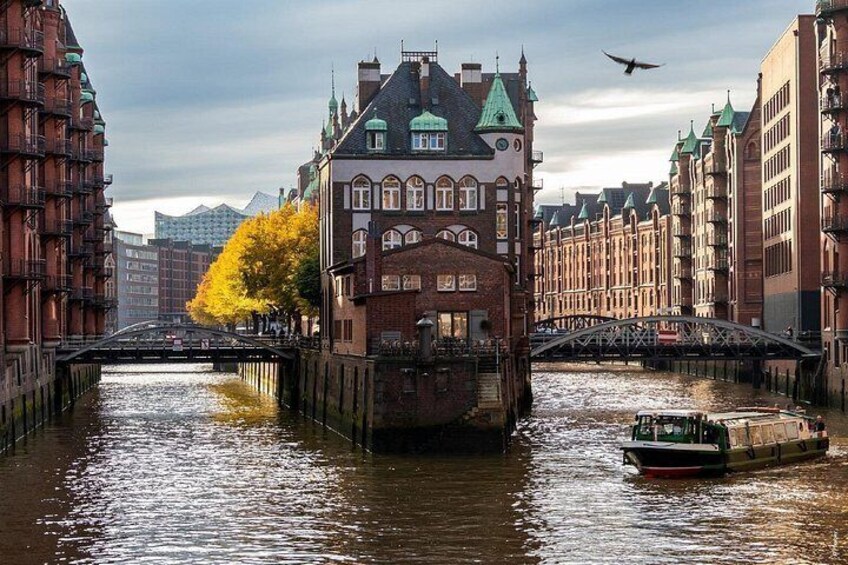 A canal with a boat, a bridge, and buildings with green roofs. 4