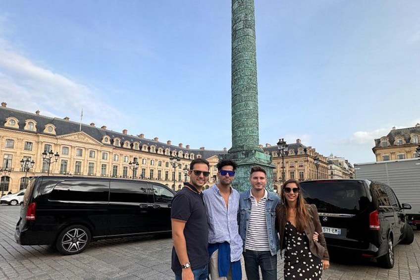 Un grupo de personas frente a un monumento alto y verde, con un edificio al fondo. 3