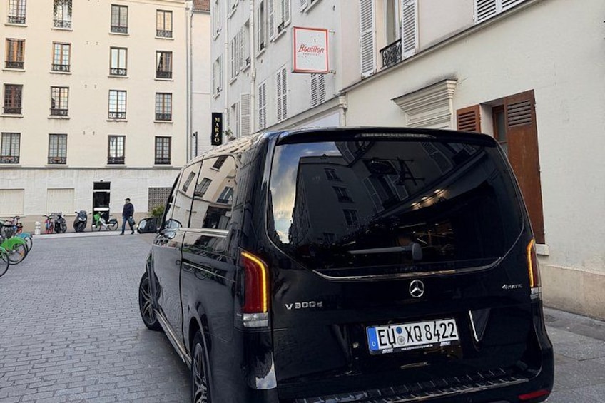 Una camioneta negra estacionada en una calle adoquinada en una zona urbana, con edificios y bicicletas al fondo. 2