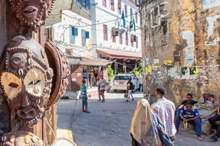 Una strada con una grande scultura decorata, palazzi con balconi e pedoni. 4
